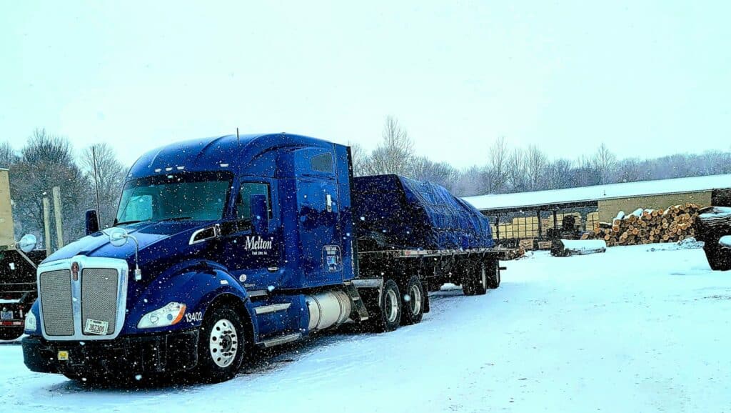 Melton Flatbed Truck Hauling a tarped load in the snow