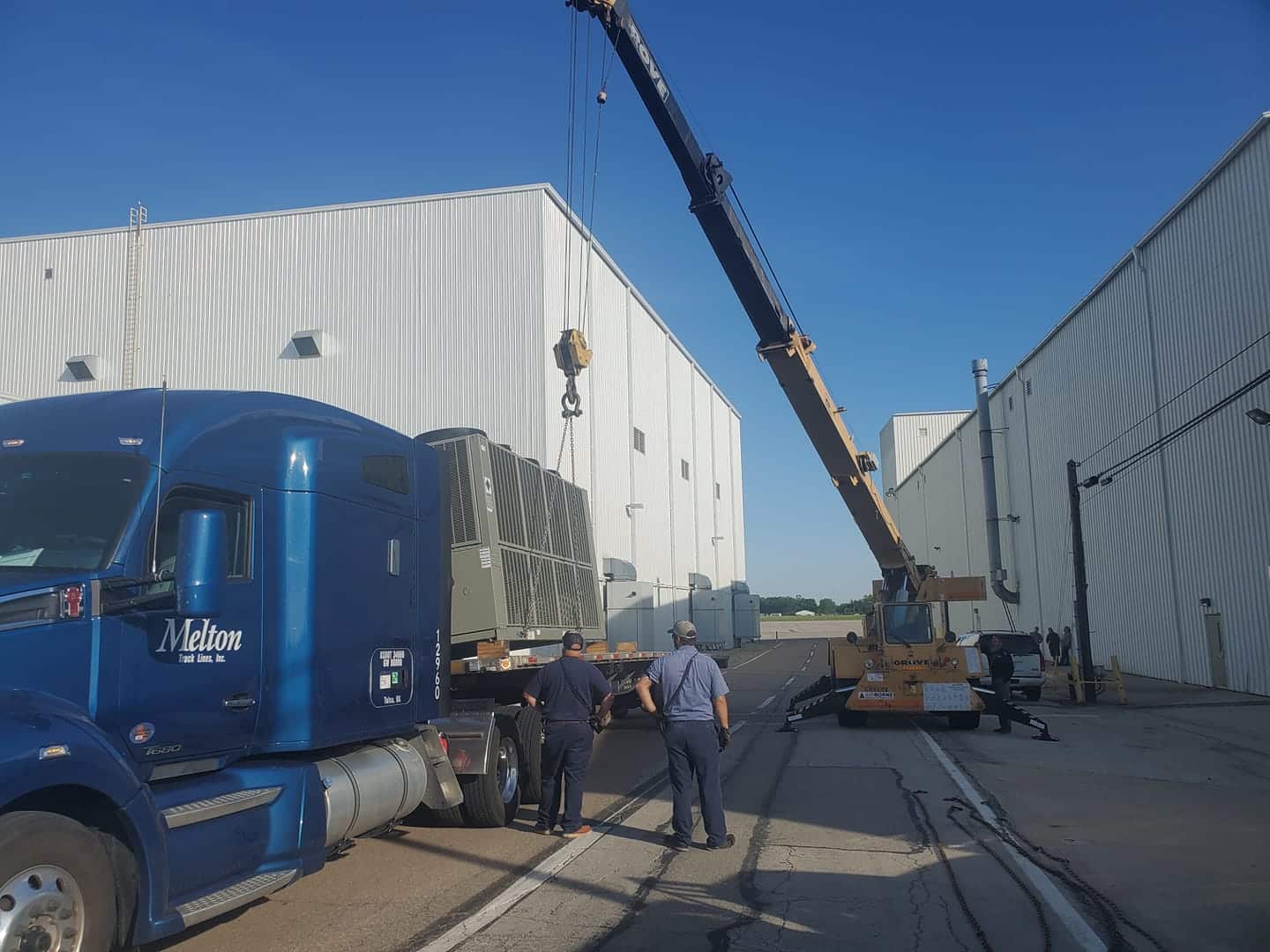 Flatbed truck getting unloaded by a crane!