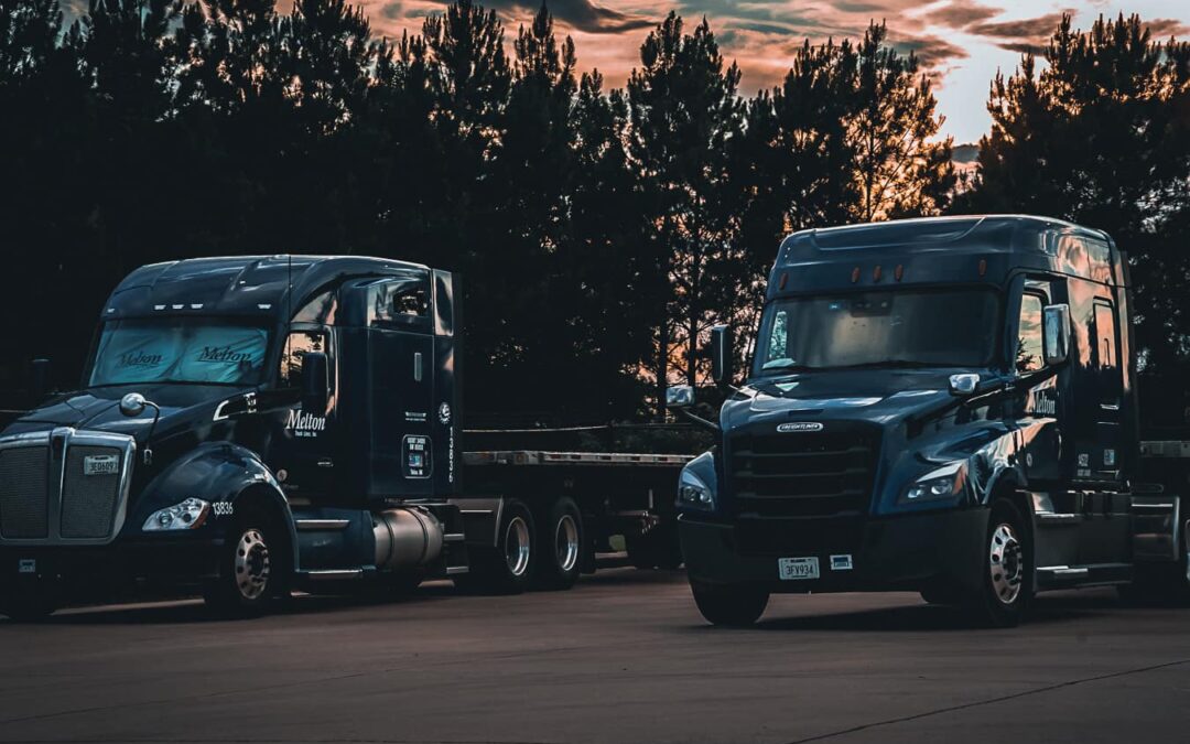 2 Melton Flatbed Trucks Parked Next to eachother