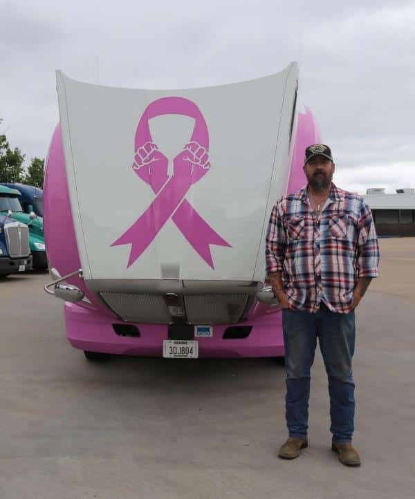 Flatbed driver standing in front of breast cancer melton truck
