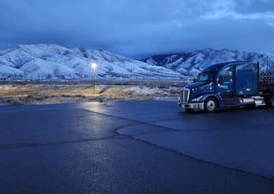 A wet parking lot with a Melton truck parked towards the right of the frame, with snowy mountains in the background