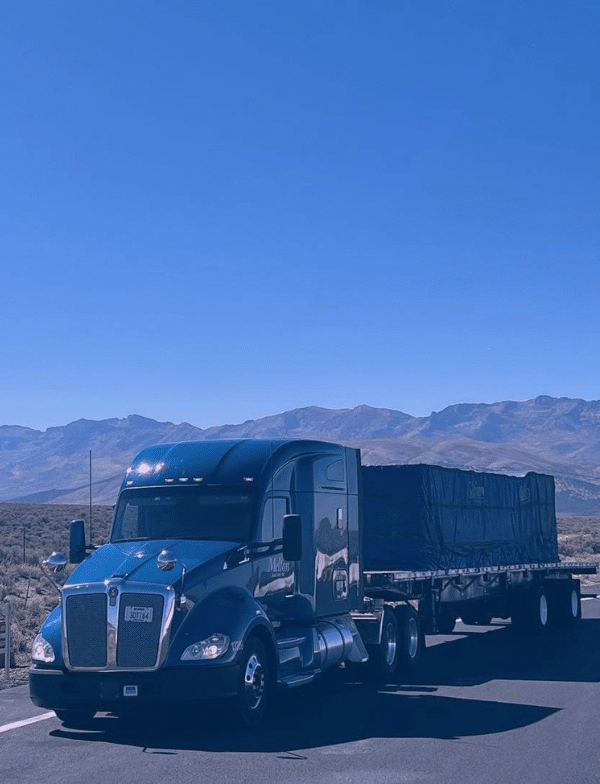 Melton flatbed truck travelling through mountains.