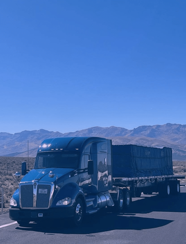 Two melton trucks backed into truck stop parking.