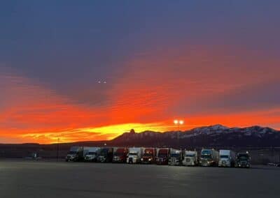 Colorful sunset with some Melton trucks parked next to each other at the base of a mountain.