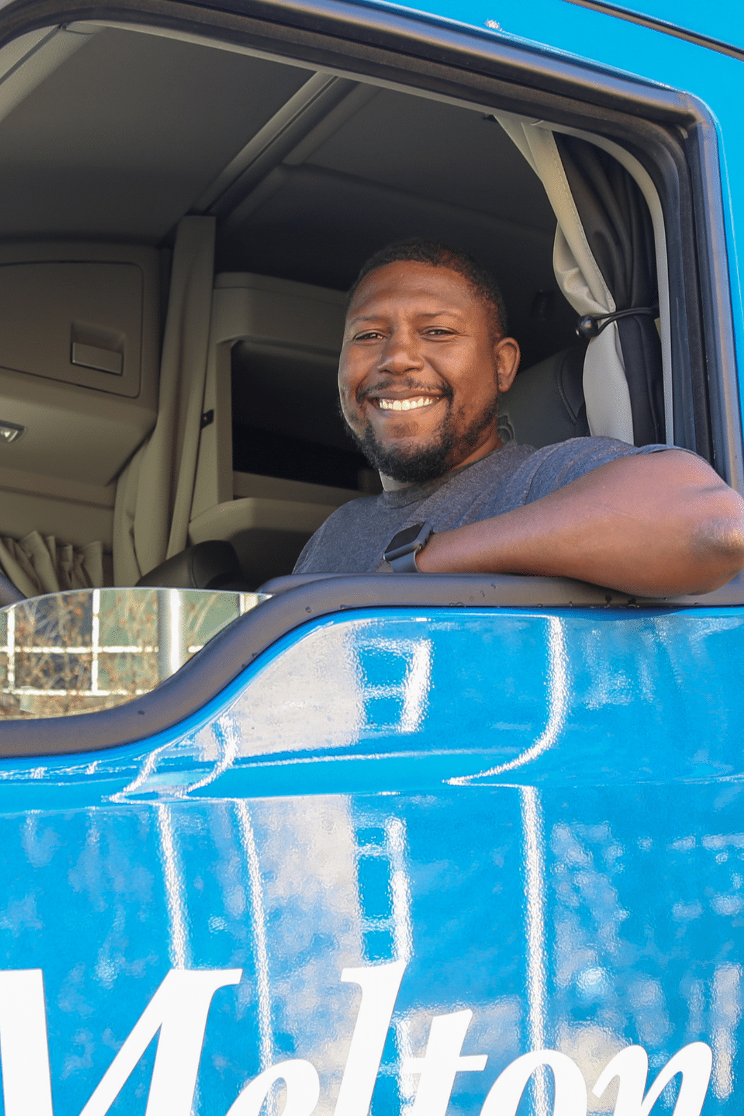 Truck OTR driver smiling in a Melton truck