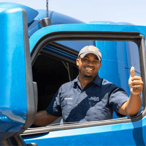 Melton flatbed truck driver holding up a thumbs up while getting into his truck