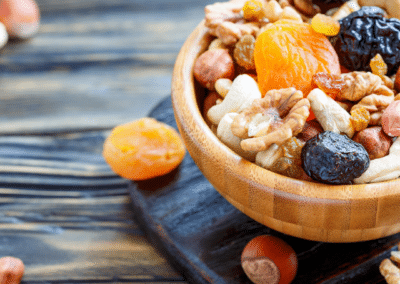 A small wooden bowl with nuts, granola, and dried fruit