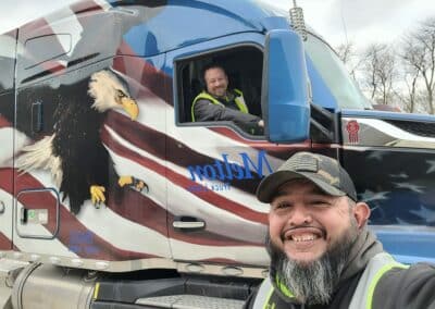 One of our veteran drivers taking a selfie with a driver inside a patriotic wrapped truck