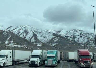 Several trucks parked at the base of a snowy mountain