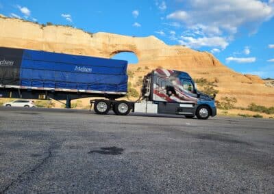 Tarped load on a Melton truck parked in front of WIlson's Arch in Utah