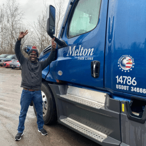 flatbed driver standing next to melton truck holding up peace signs