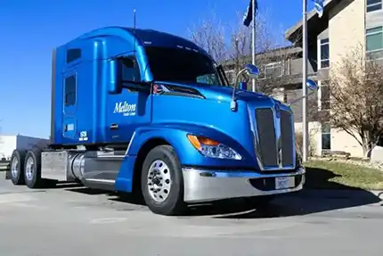 Dark blue semitruck with Melton logo parked in front of the Melton headquarters
