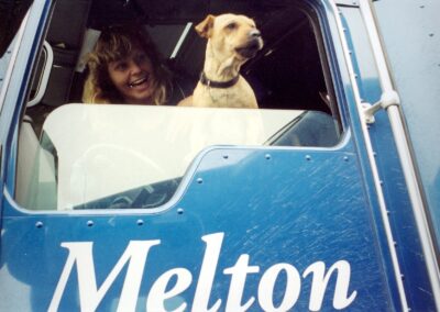 Dog looking out of the driver's side window of a Melton truck