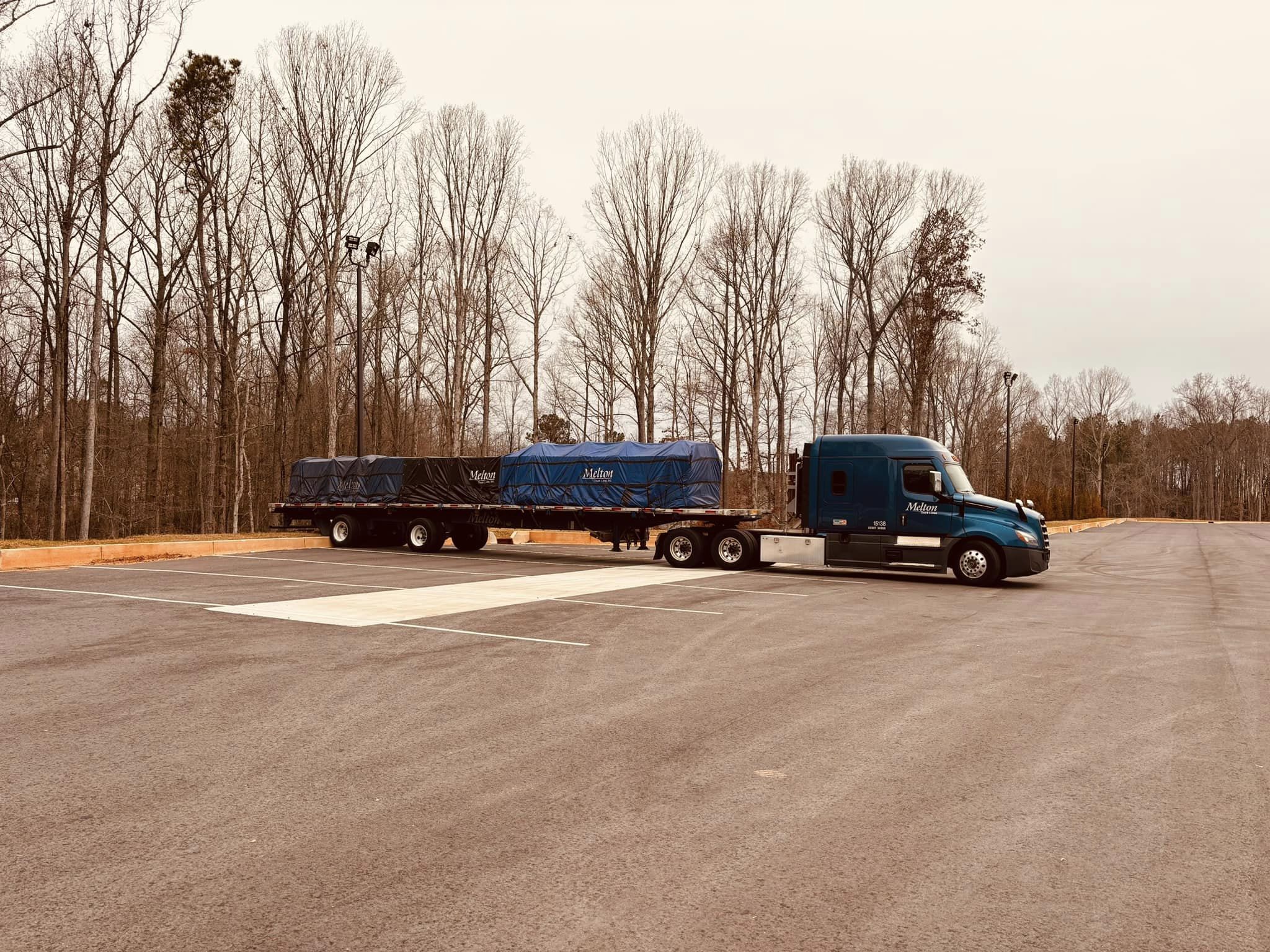 A Melton truck parked on a lot by some dead trees