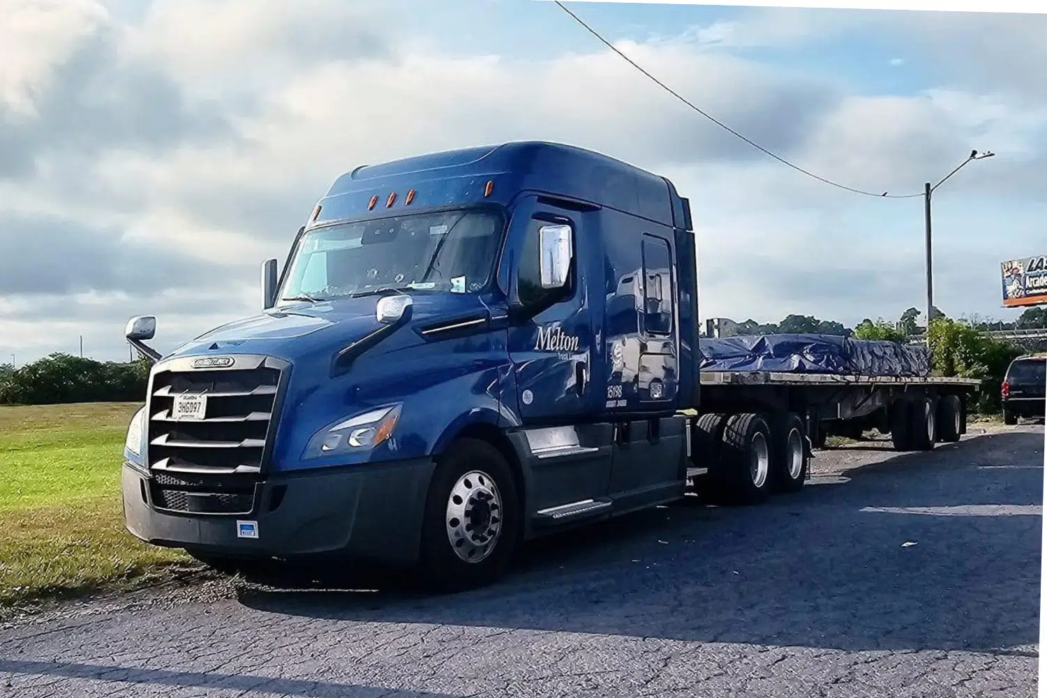 Blue Melton truck parked with a tarped load