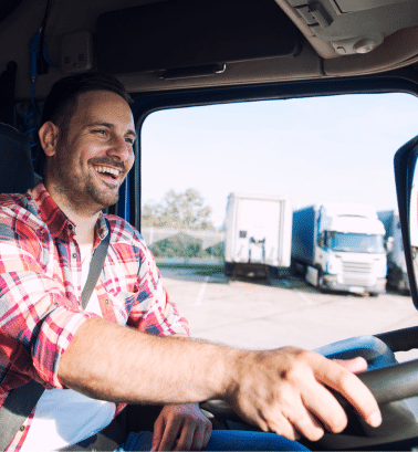 A man in a flannel driving a semi truck