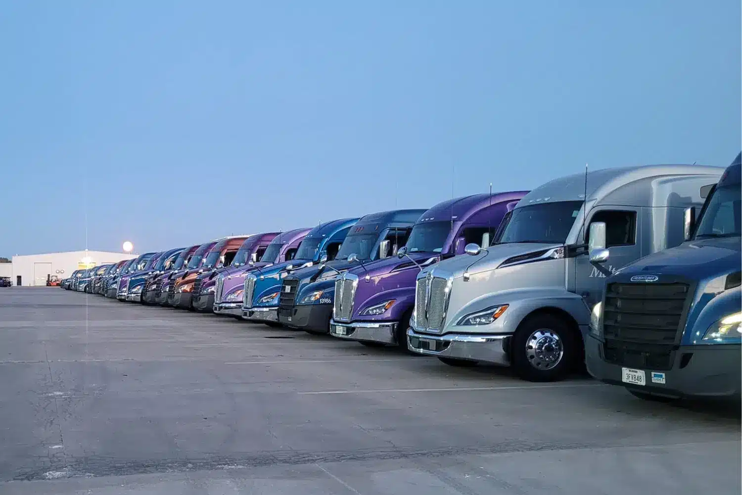 A row of Melton trucks in a variety of colors parked in a lot.