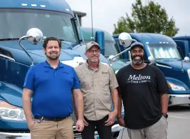 Three Melton employees standing in front of a parked Melton truck.