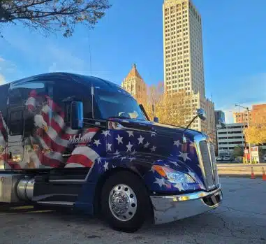 A patriotic Melton truck parked in front of a city skyline