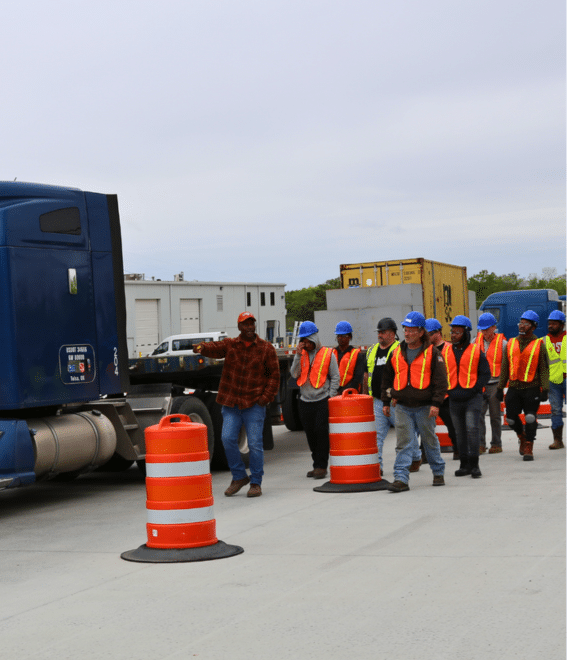 Truck driving instructor leading students towards a truck