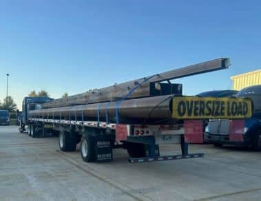 Melton truck with a load of steel beams and an OD banner