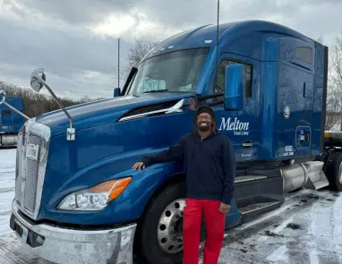 Driver standing in front of a Melton truck in the snow