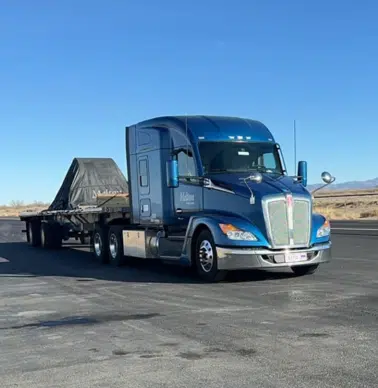 A Melton truck parked on asphalt with a tarped load