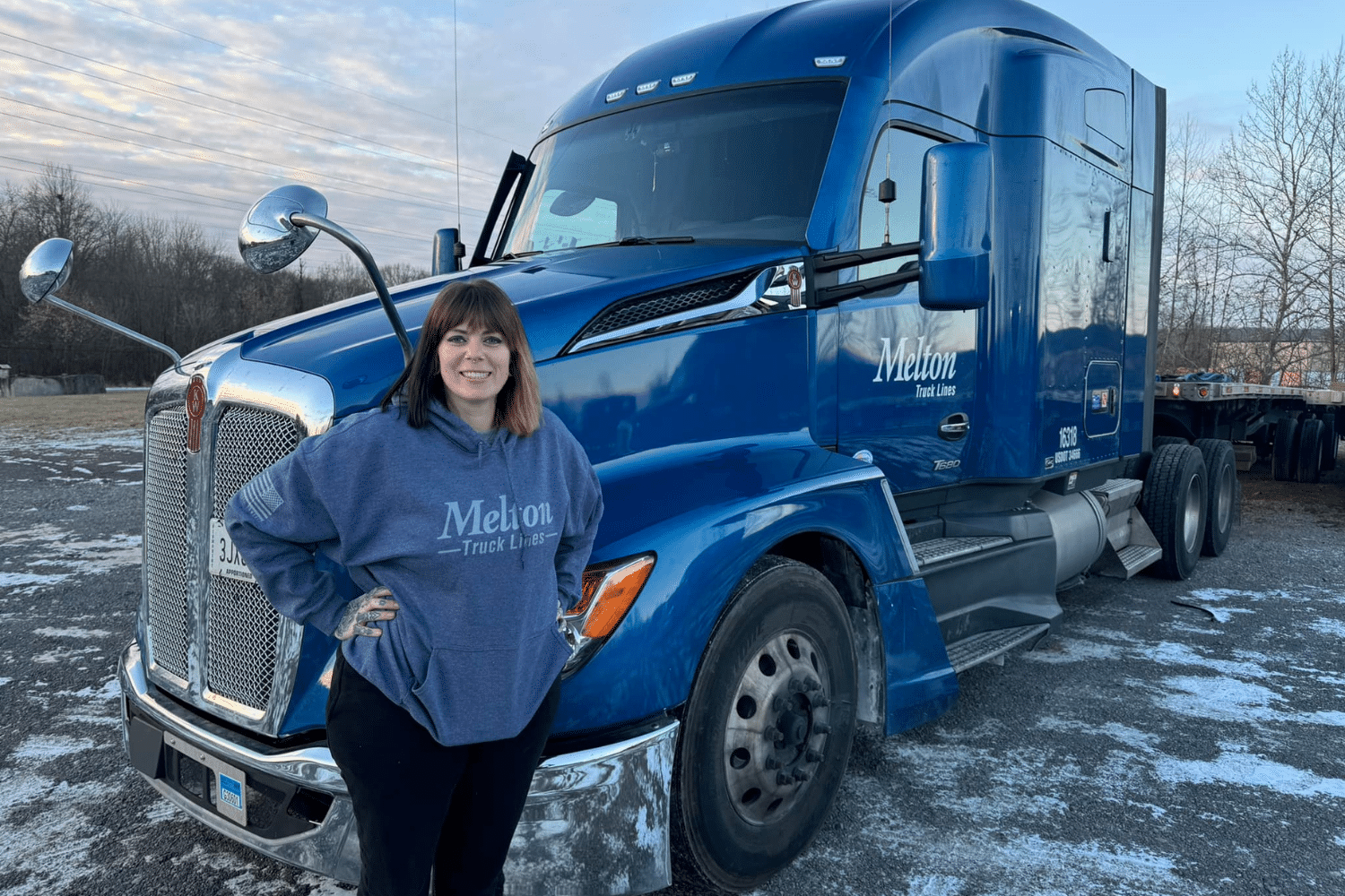 Driver wearing a Melton hoodie standing in front of her truck