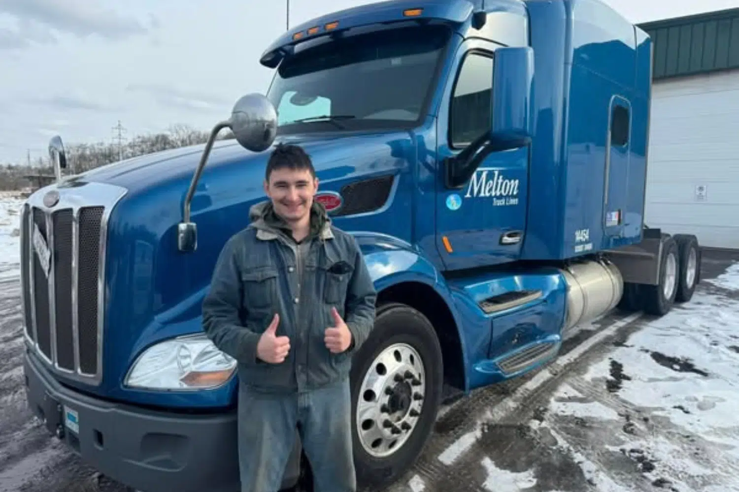 A Melton driver in front of a truck with two thumbs up in the snow