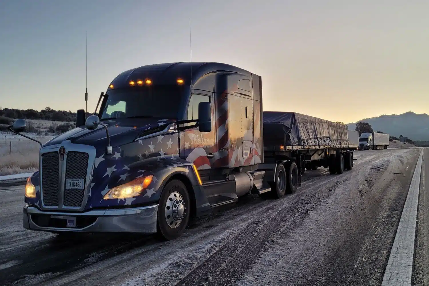 A Melton truck with a patriotic wrap pulling a secured load