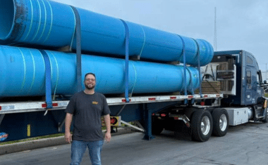 Melton driver standing in front of a loaded flatbed truck