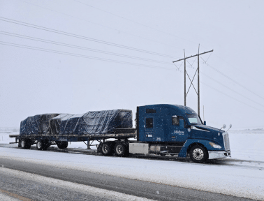 A Melton truck with a tarped load in the snow