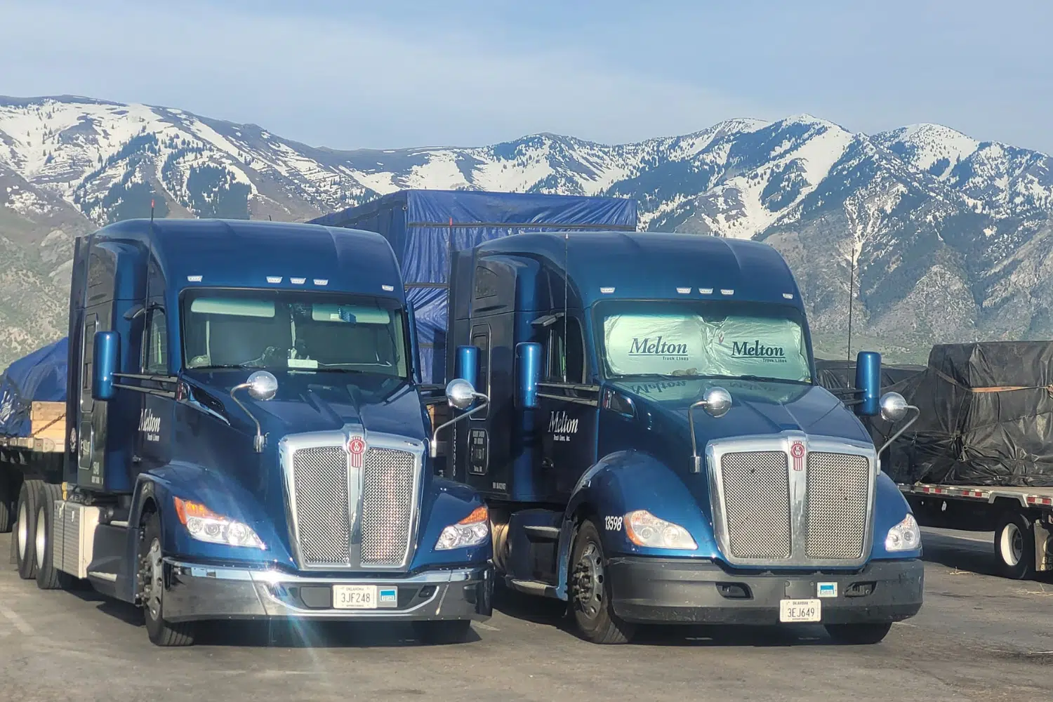 Two Melton trucks parked in front of a mountain