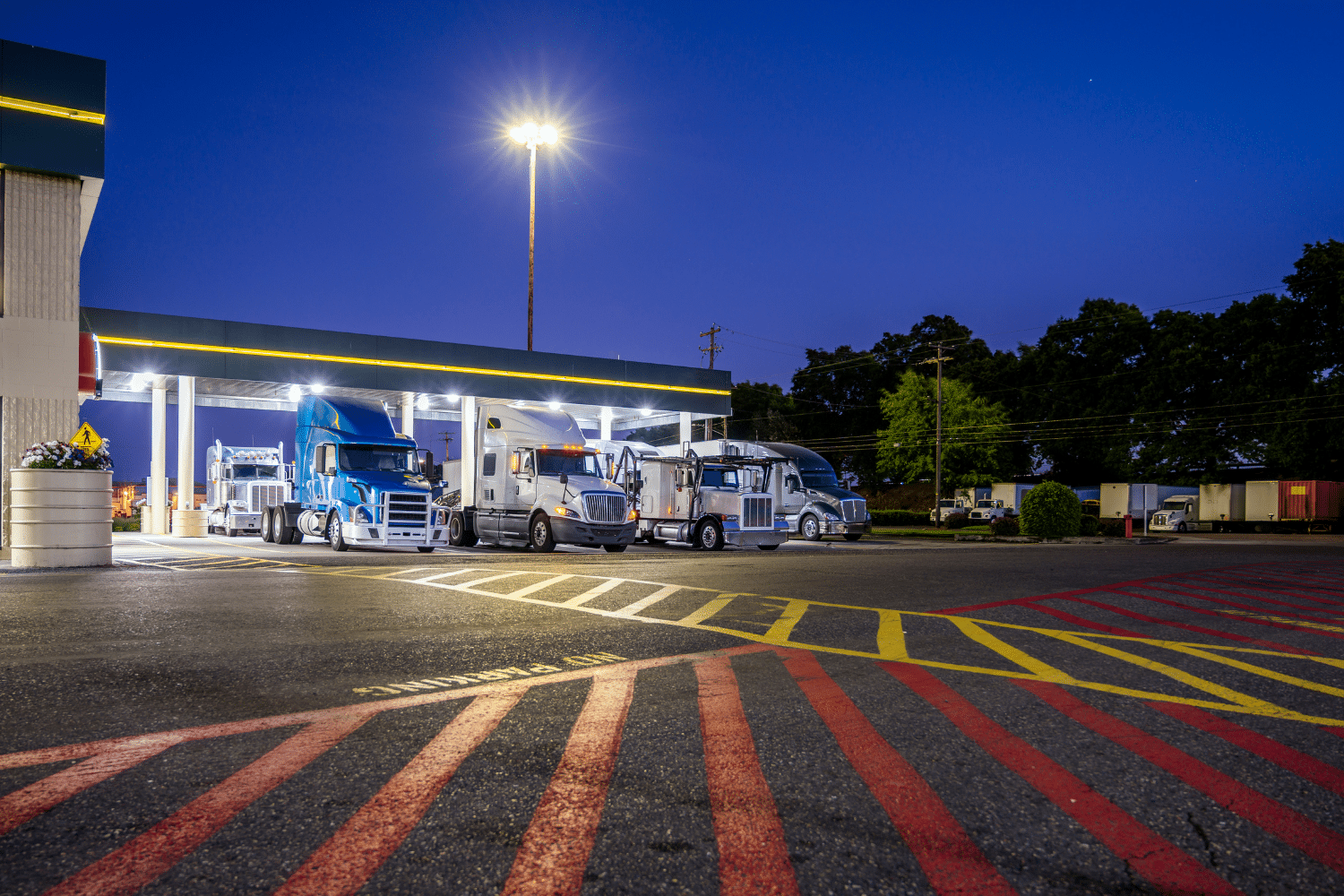 A truck stop at night with several trucks parked