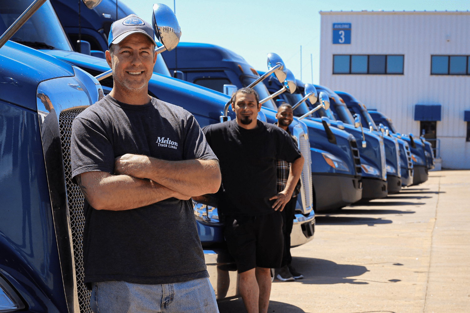 Melton drivers standing in front of flatbed trucks