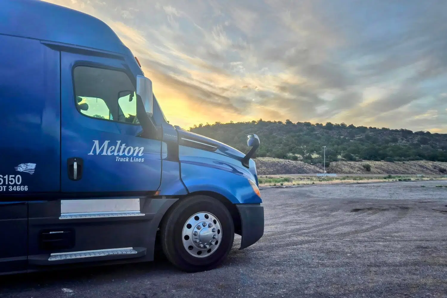 Melton flatbed truck parked with a sunset in the background